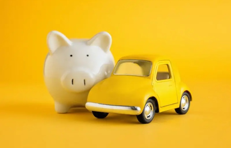 Salvadanaio bianco e auto giocattolo gialla su sfondo giallo